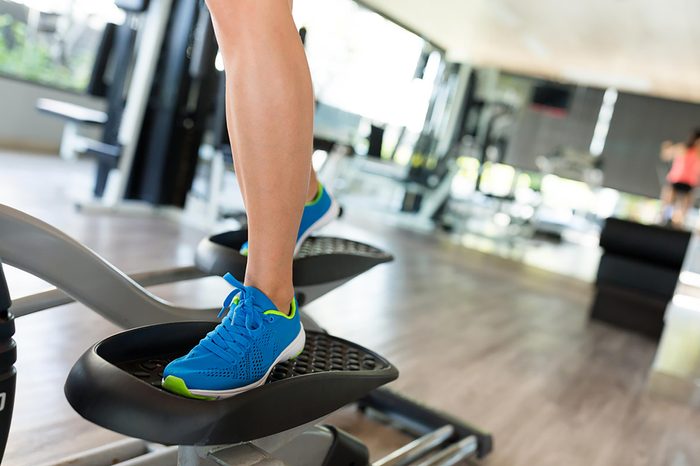 Woman in blue shoes using the elliptical.