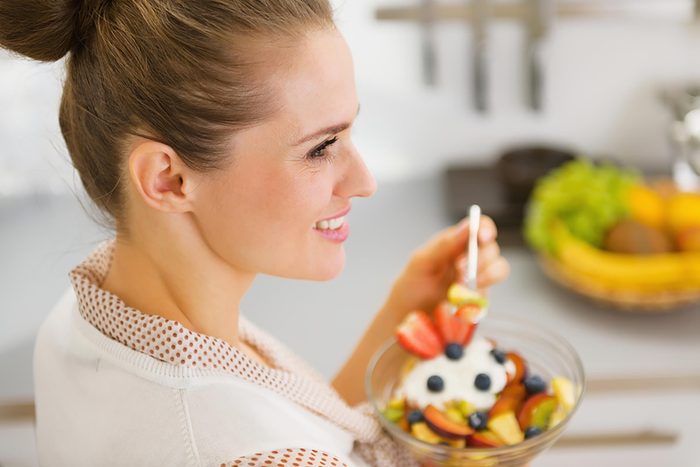 woman eating a bowl of fruit with yogurt