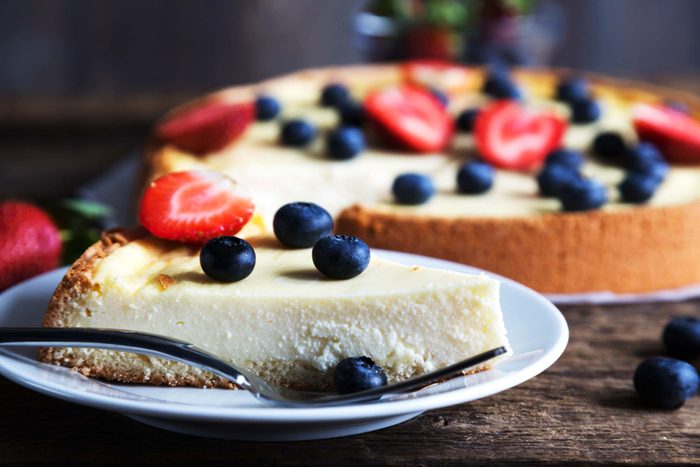 Cheesecake topped with fruit and a slice on a plate.