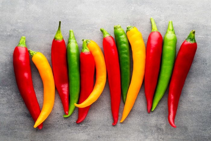 line of red, yellow, and green chili peppers on a gray background