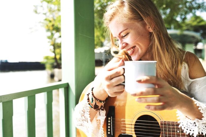 Woman with mug and guitar on a porch