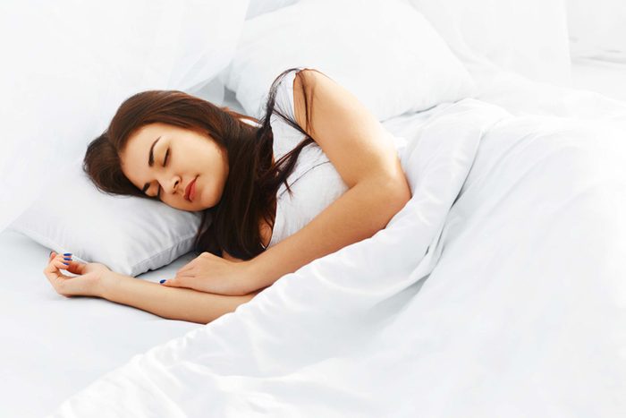 woman asleep in a bed with all white sheets