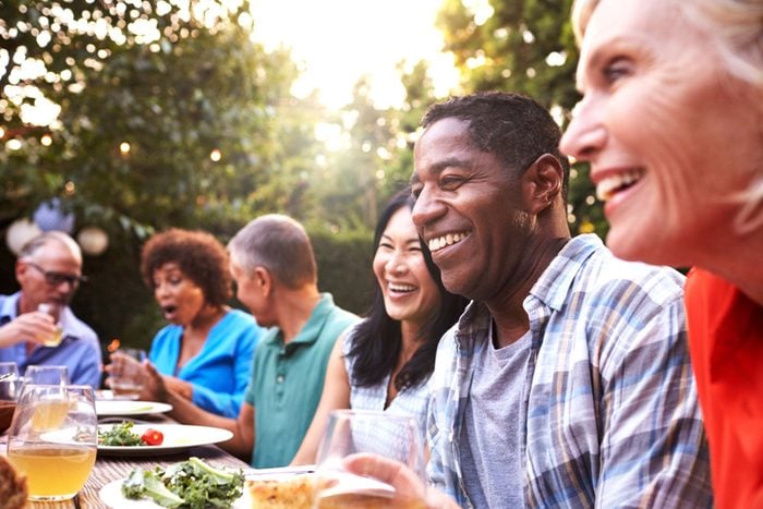 group of friends gather for a meal in a backyard