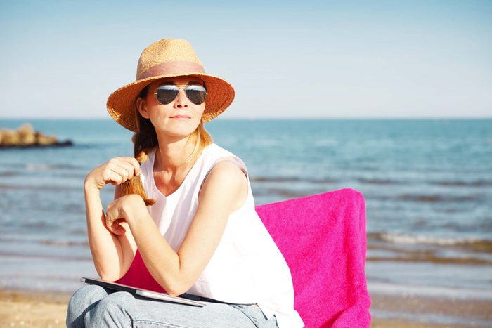 woman sitting in a chair on the beach gazing into the distance
