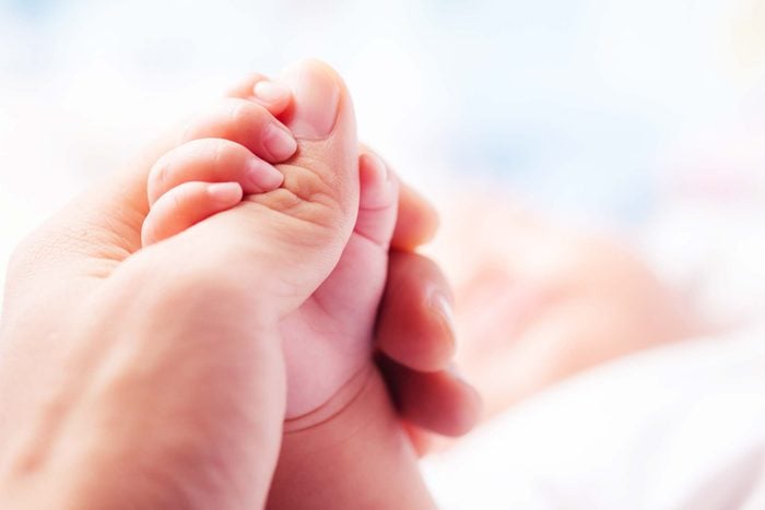 tiny newborn hand wrapped around an adult thumb