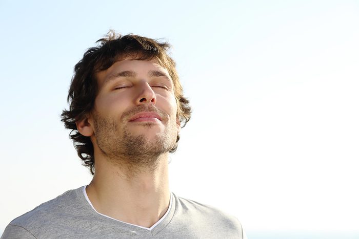man outdoors in the sun breathing deeply