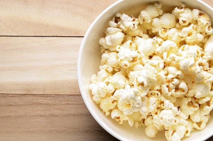 white bowl of popcorn on a wood surface