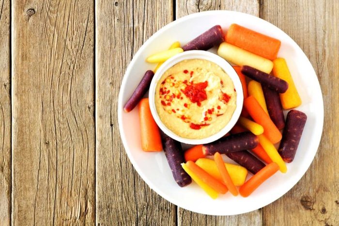 plate of various-colored carrots with bowl of hummus