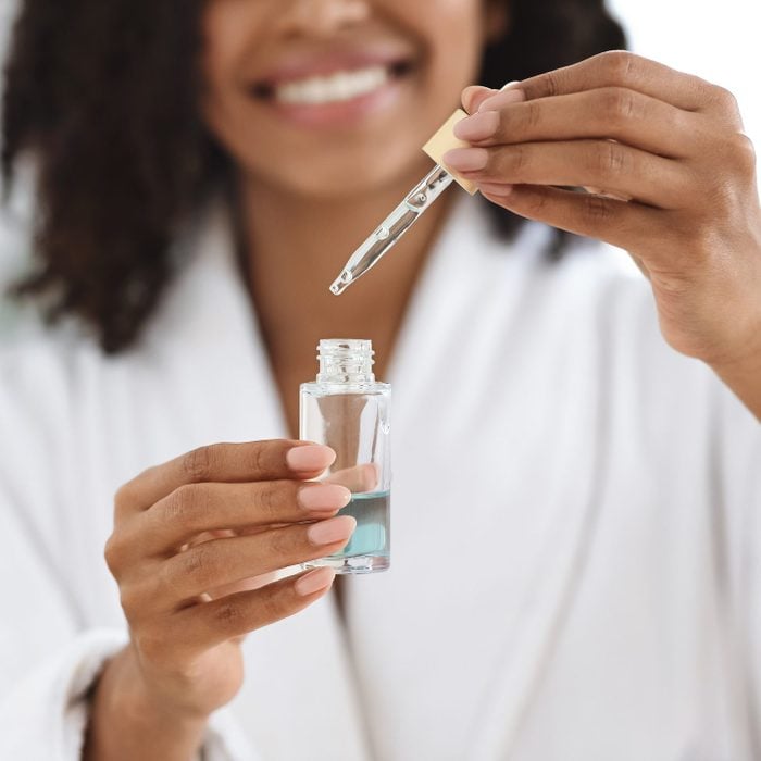 woman holding face serum bottle and pipette