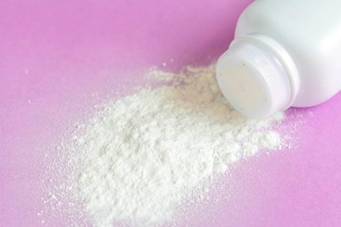 talcum powder spilling out of a bottle on a pink surface