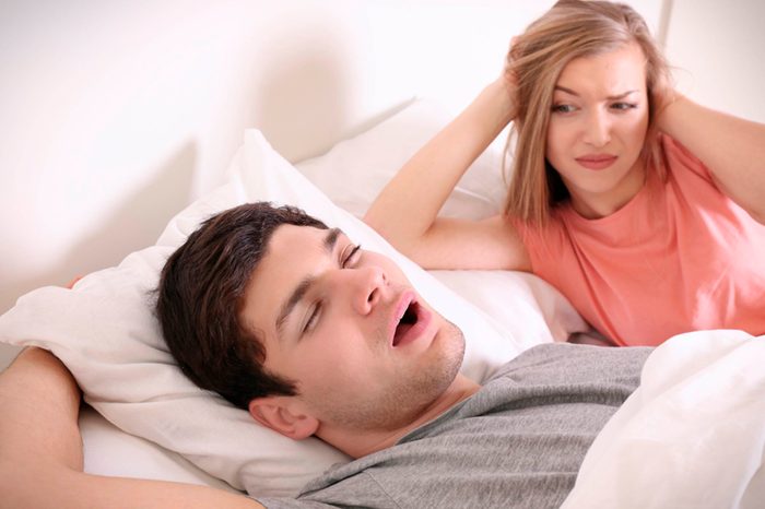 woman looks annoyed as man snores with mouth open