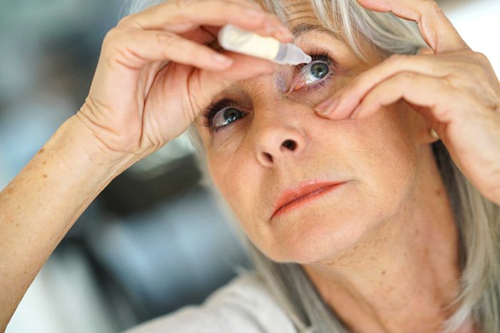 elderly woman applying eye drops
