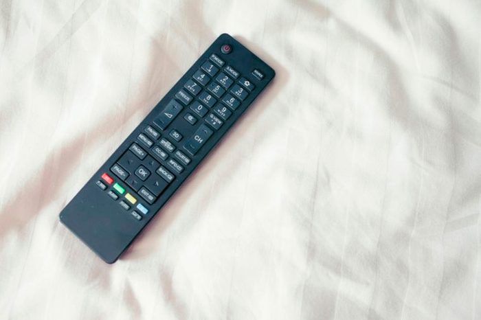 TV remote control on top of white sheets