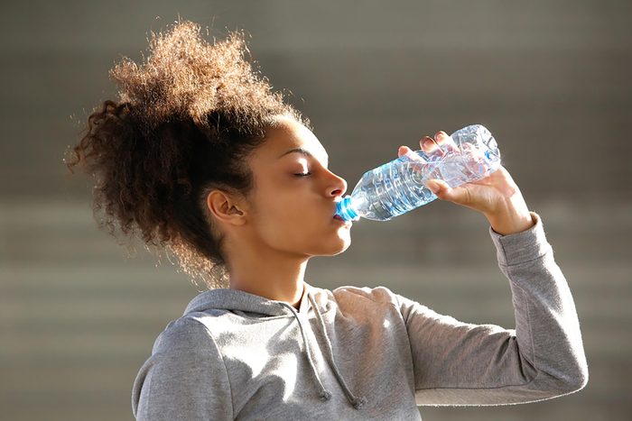Woman athlete drinking from plastic bottle of water