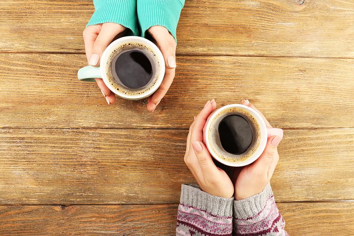 Two sets of hands holding cups of coffee