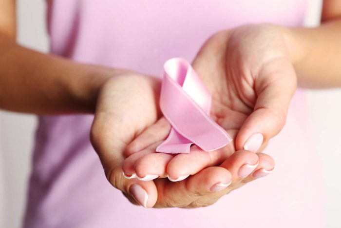 woman's hands holding pink ribbon