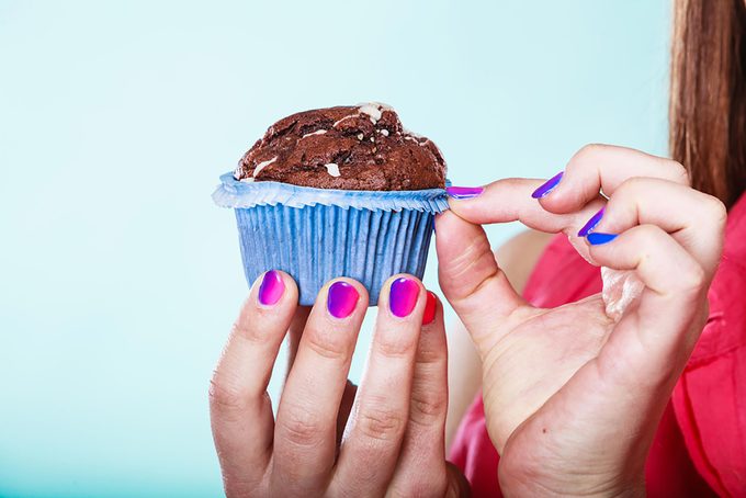 person unwrapping cupcake