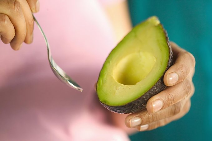 person eating avocado with spoon