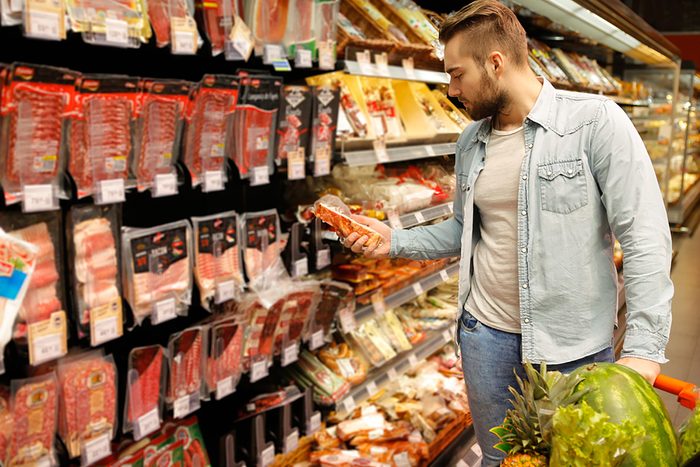 man reading food label in store