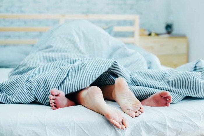 man and woman under the covers, only feet showing