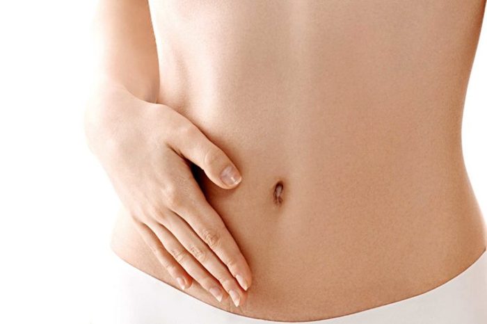 Woman placing a hand on her flat stomach.