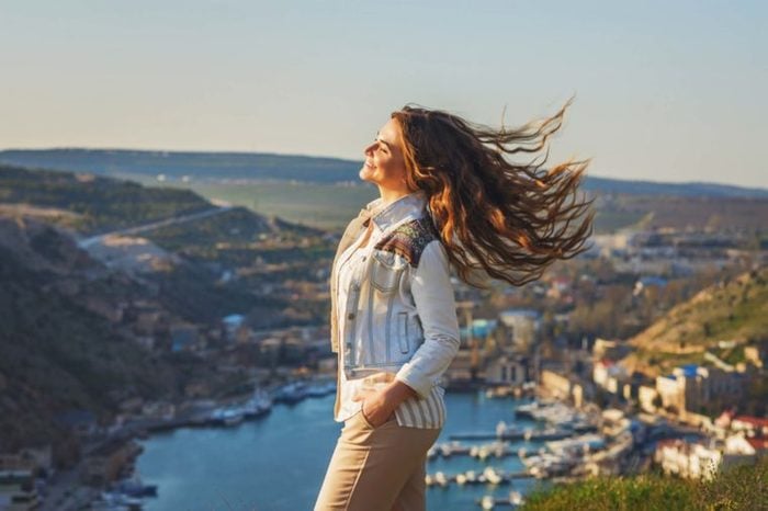 woman smiling on the top of a hill with a nice view