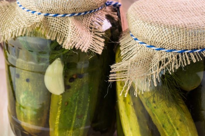 Jars of pickle juice covered with burlap lids.