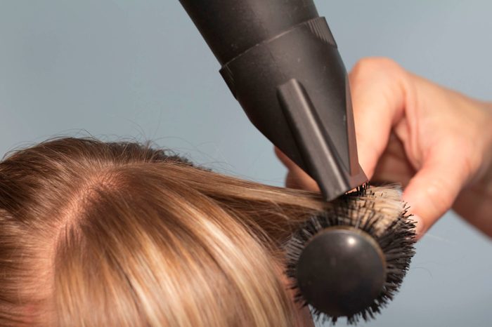 stylist drying hair with round brush