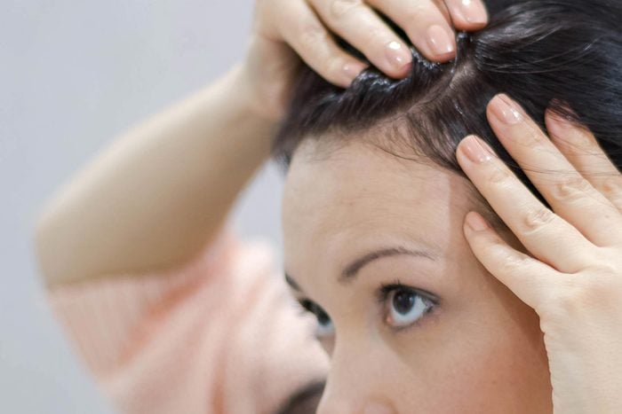 woman examining hair on scalp