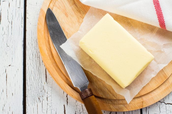 block of butter or margarine on cutting board with knife