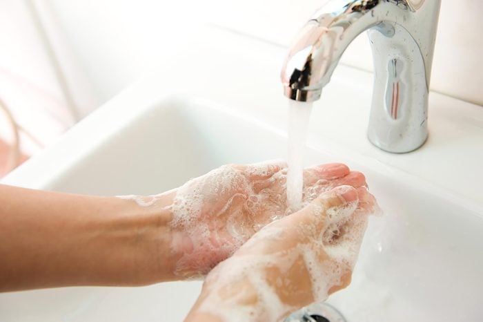 soapy hands in a sink under a faucet 