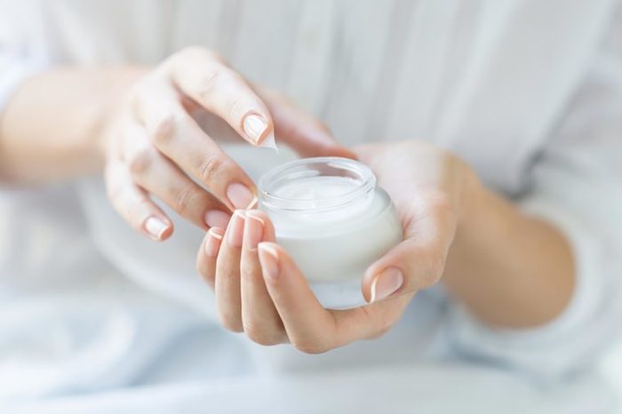 woman's hands holding a bottle of moisturizer