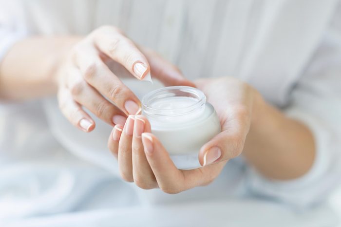 woman holding a jar of white cream / niacinamide