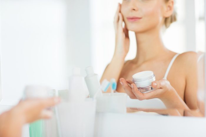 woman looking into the mirror and applying Moisturizer