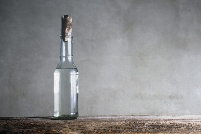 vinegar in a corked, clear glass jar on a wooden surface