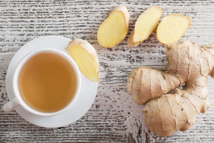 Ginger root, slices, and ginger tea in a white teacup