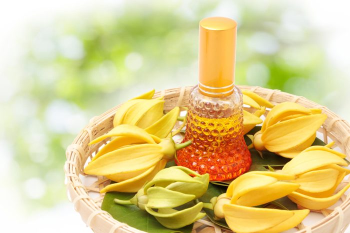 ylang ylang oil in a bottle surrounded by flowers on shallow basket