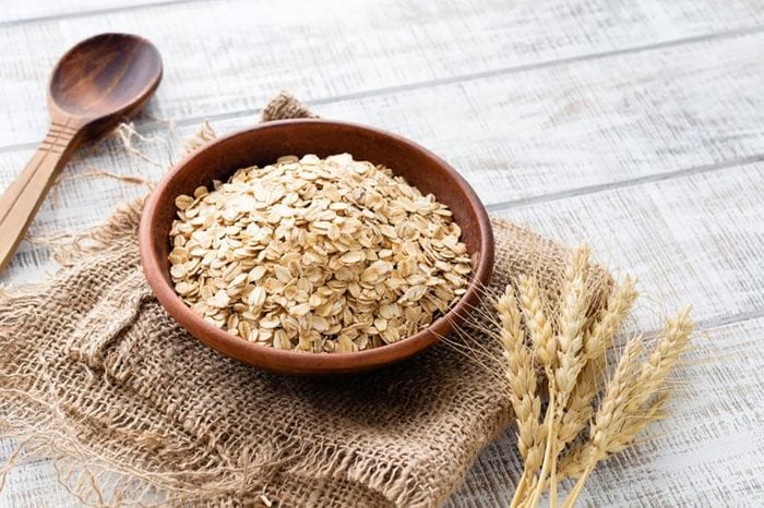 dry oats in a wooden bowl on a folded burlap sack
