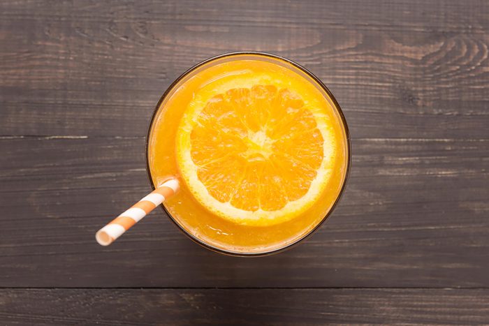 glass of orange juice with orange slice and straw