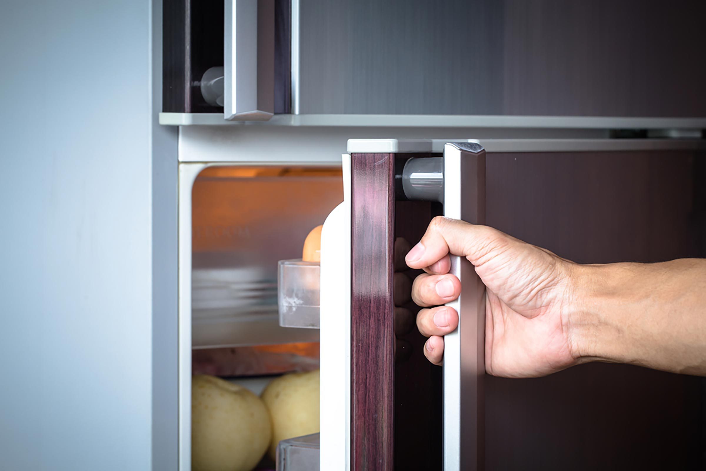 человек открывает холодильник