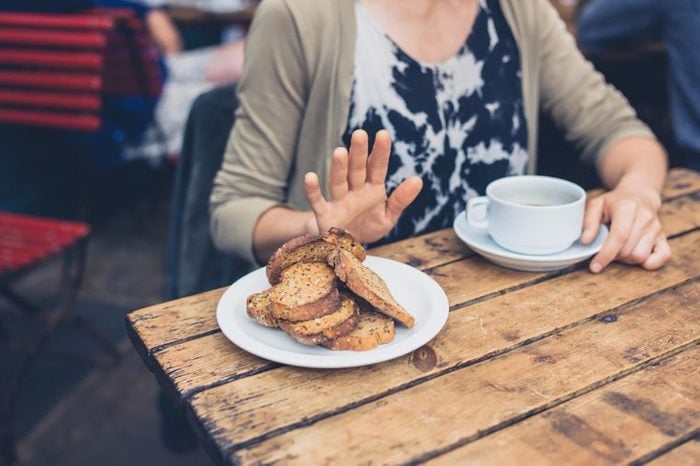 woman at breakfast holding her hand up to toast