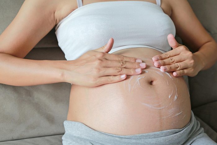pregnant woman rubbing cream into her belly