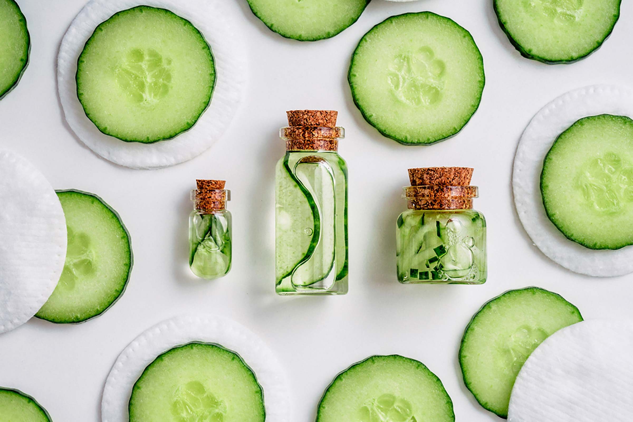 Cucumber slices artfully arranged around jars containing cucumber liquid