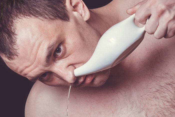 Man using a neti pot in his nostril.