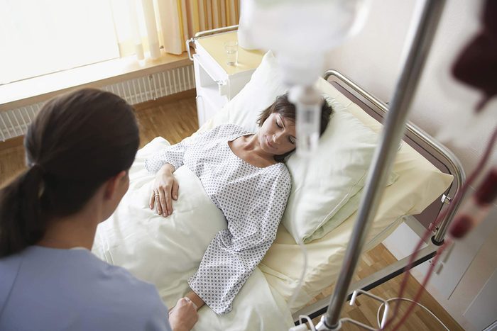 Woman lying in a hospital bed with an IV drip.