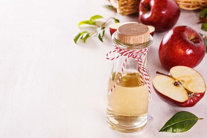 glass bottle of Apple cider vinegar with apples in background