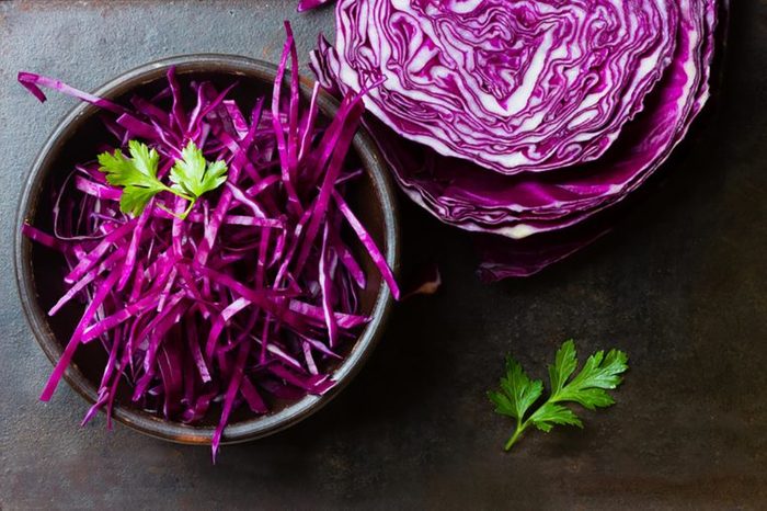 shredded purple cabbage in bowl and half the head