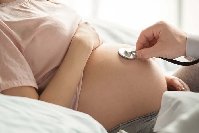 Arzt untersucht den Bauch einer schwangeren Frau mit einem Stethoskop