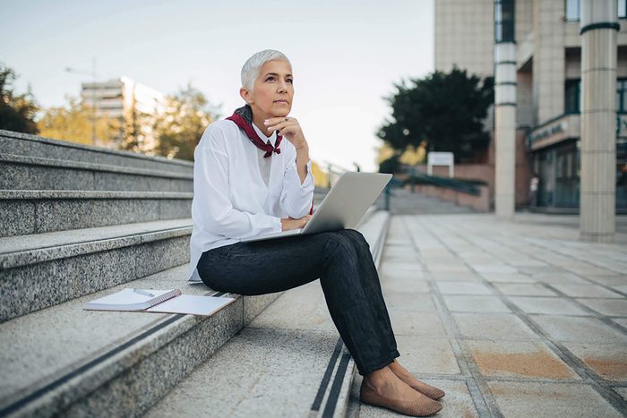 thoughtful gray-haired woman with laptop