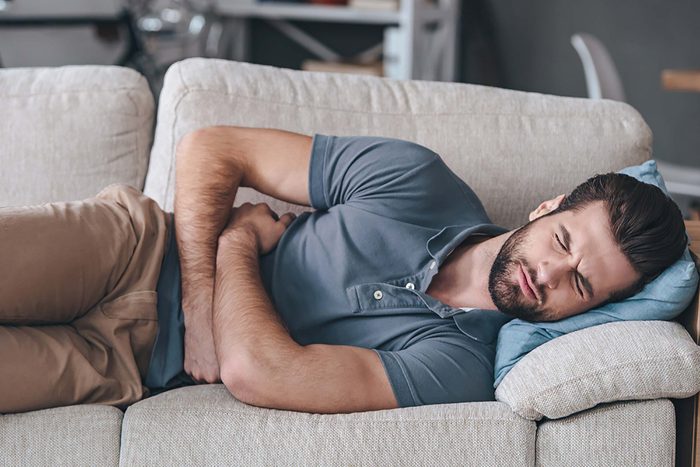 man on couch with stomach pain